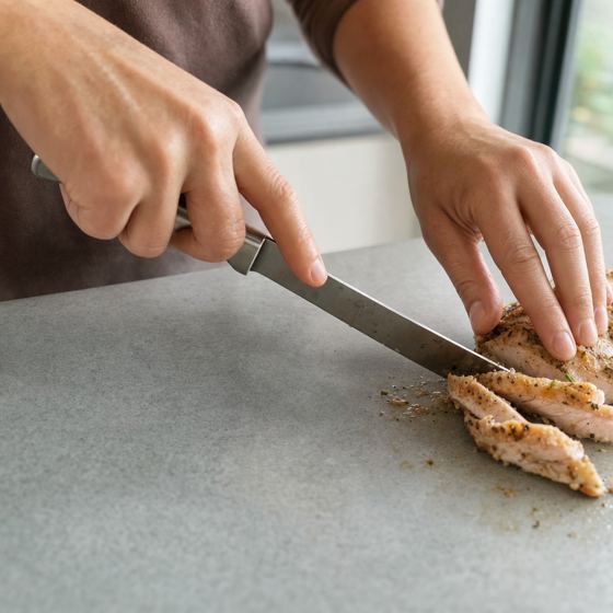 A knife cutting food directly on the sintered stone surface